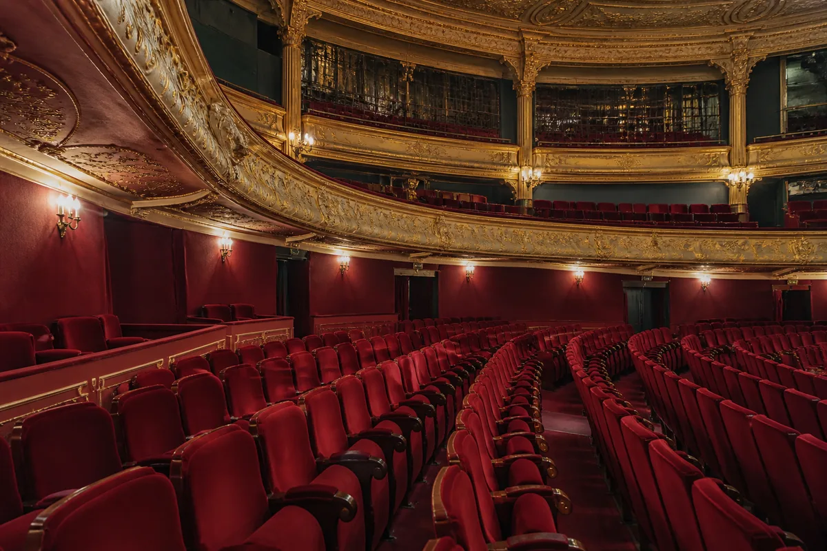 Rangées de fauteuils rouges dans une salle de théâtre à l&rsquo;italienne vide, lumière de service